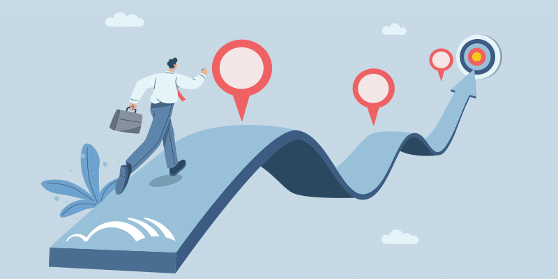 A businessperson walks along a winding path marked with location pins, moving toward a target symbol positioned at the path's endpoint.